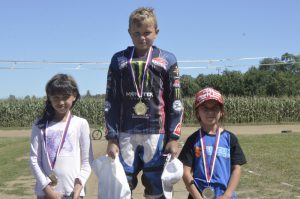 První závody, první vítězství, Kostěnice v červenci 2018 stojí na pódiu kategorie Junioři Flat Track: Denisa Maclová, Dominik Hrbek a Ela Kňávová